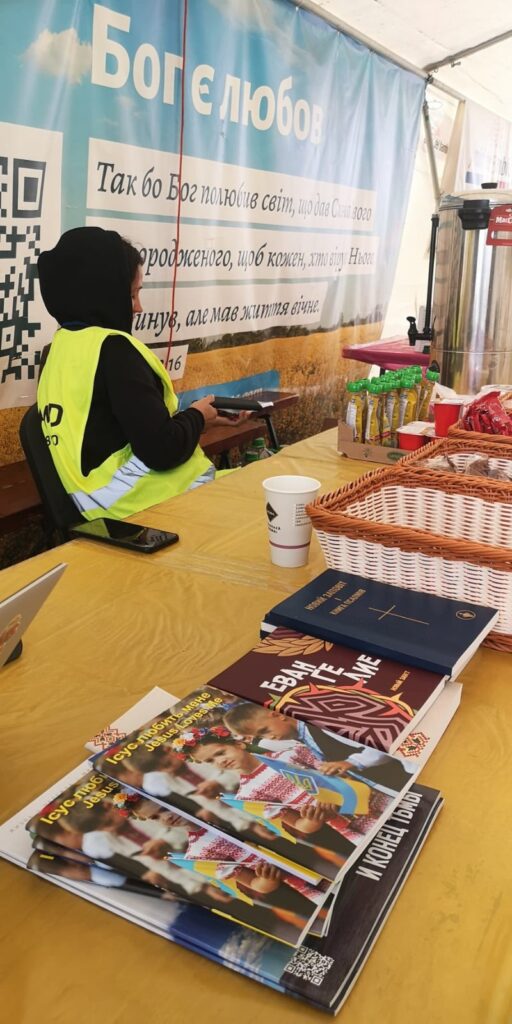 Table of food and spiritual material at Moldova-Ukraine border, October 2022. The sign on the wall is John 3:16 in Ukrainian.