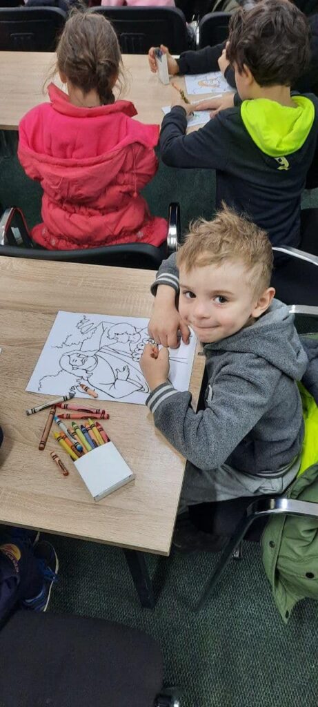 At the Vatici Center, refugee child colors a Bible story about Jesus and children